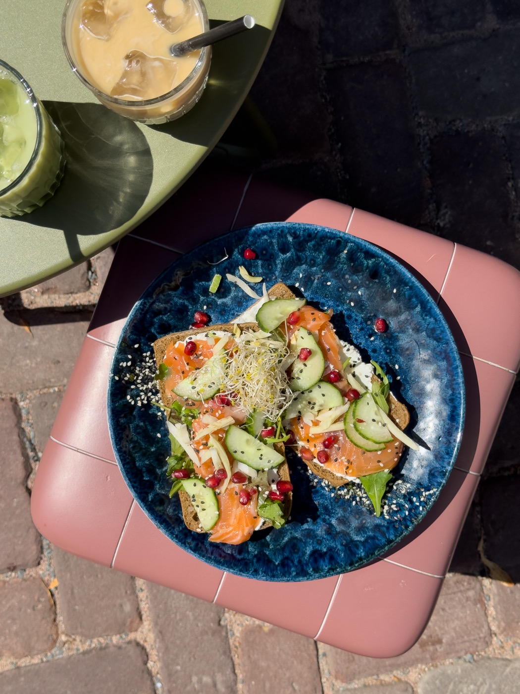 Toast met zalm, komkommer en granaatappel op een blauw bord